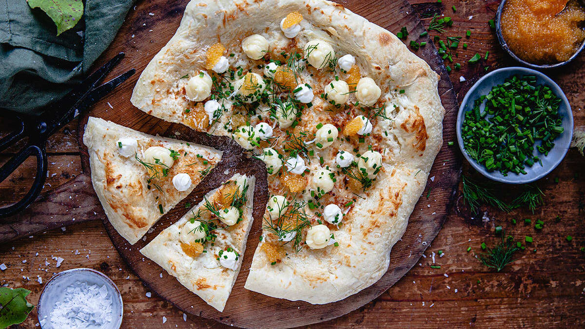 Hjemmelaget pizza med lakserogn, crème fraîche og rødløk